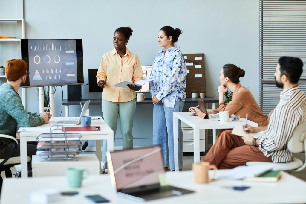 Young confident teacher or coach standing in front of audience at seminar